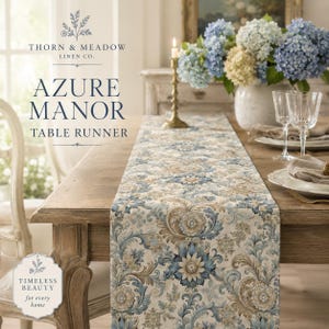 Puede incluir: Un camino de mesa con un patrón floral y de volutas repetitivo en tonos azul, beige y crema. El texto en la imagen dice: THORN & MEADOW LINEN CO. AZURE MANOR TABLE RUNNER y TIMELESS BEAUTY for every home.
