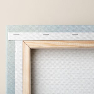 Close-up of the back of a stretched canvas showing wooden frame and hanging hardware, highlighting craftsmanship and hanging readiness.