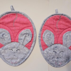 May include: Two pink and gray mouse-shaped pot holders with embroidered eyes and noses.