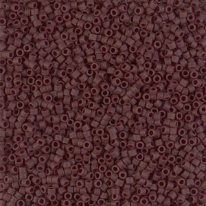 May include: Close-up of a pile of small, cylindrical beads in a deep burgundy color. The beads are uniform in size and shape, with a hole running through the center of each. These beads are suitable for jewelry making and crafting.