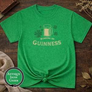 Funny Running on Guinness St Patrick’s Day shirt featuring a beer mug and shamrock design printed on Gildan 5000 unisex t shirts available in black white Irish green and antique Irish green colors, humorous Irish drinking shirt perfect for St Paddy’s Day pub crawls parties festivals and Irish holiday celebrations.