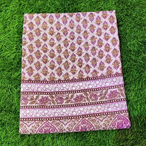 Peut inclure: Un tissu en coton rose et marron avec un motif floral. Le tissu a une bordure avec un motif r&eacute;p&eacute;titif de fleurs et de feuilles.