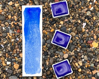 May include: A watercolor paint pan with a blue pigment sample and the text "ULTRAMARINE BLUE".