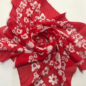 May include: A red sheer scarf with white floral print and white lace trim.