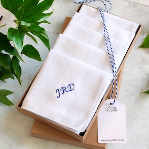以下が含まれることがあります： 茶色の箱に入った、青い刺繍のイニシャル「JRD」が入った白いハンカチのセット。箱は青と白の紐で結ばれ、「Amys Gifts」と書かれたタグが付いています。
