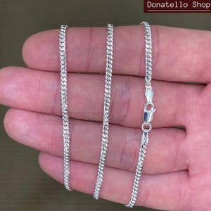 May include: A silver curb chain necklace with a lobster clasp closure.