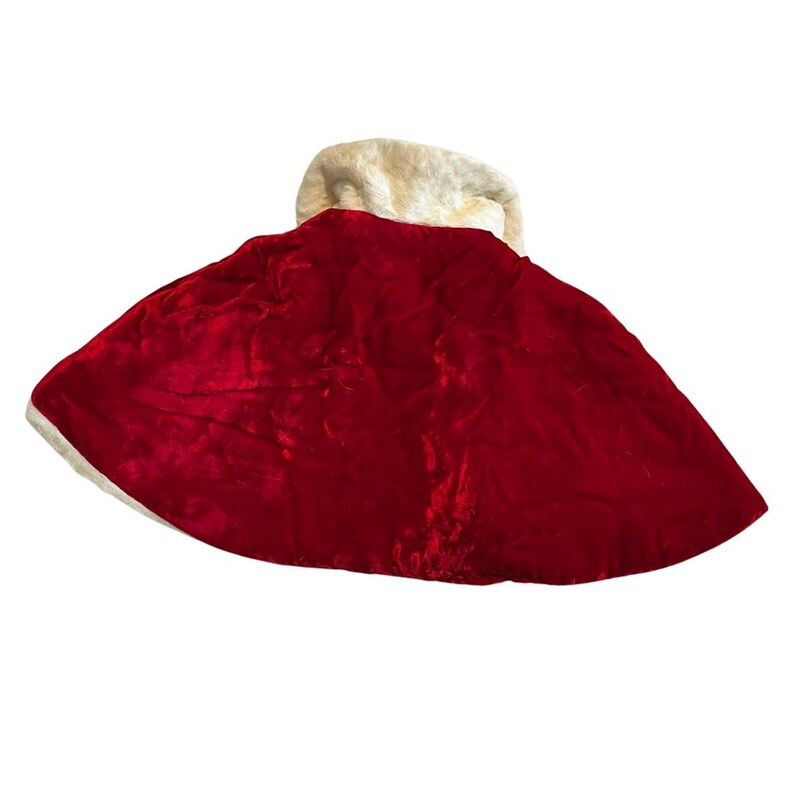 May include: A red velvet cape with a white faux fur collar and trim. The cape is a deep red color and has a soft, flowing texture. The white trim adds a contrasting element to the design. This cape is suitable for costumes or festive occasions.