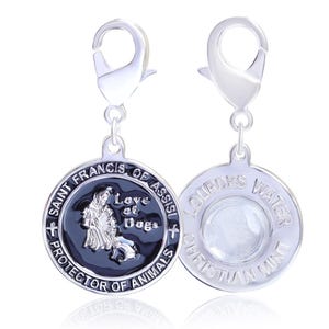 Puede incluir: Dos colgantes plateados con cierres de mosquet&oacute;n. Un colgante presenta un fondo negro con el texto "Saint Francis of Assisi, Protector of Animals" y una representaci&oacute;n de San Francisco con un perro. El otro colgante tiene el texto "Lourdes Water Christian Mint".