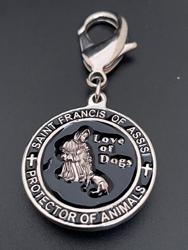 Puede incluir: Un dije plateado con un centro negro, que presenta una imagen de San Francisco de As&iacute;s con un perro. El dije dice "Saint Francis of Assisi Protector of Animals" y "Love of Dogs". Incluye un cierre plateado.