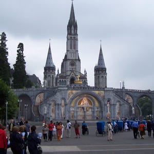 Puede incluir: Una gran catedral ornamentada con m&uacute;ltiples agujas y una fachada detallada. El edificio es de piedra gris, con pasarelas arqueadas y una gran plaza delante. La gente camina por la plaza.