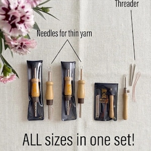 Op de afbeelding: Een set punch-naaldgereedschap met houten handvatten en metalen punten, inclusief naalden voor dun garen en een draadinrijger. De set zit in plastic hoesjes en een zwart tasje. De tekst luidt: Needles for thin yarn, Threader, ALL sizes in one set!