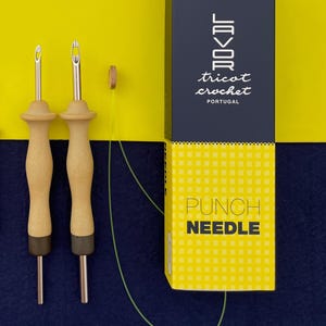Op de afbeelding: Twee ponsnaalden met houten handvatten en metalen punten, een kleine houten cirkel en een groen touwtje. De naalden zijn verpakt in een gele en zwarte doos met de tekst "tricot crochet" en "PUNCH NEEDLE".