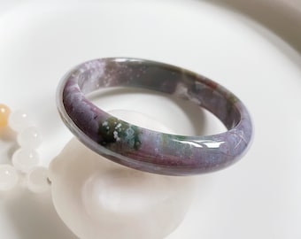 May include: A purple, green, and white agate bangle bracelet. The bracelet is smooth and polished.