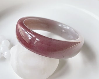 May include: A smooth, polished jade bangle with a gradient of pink and white colors.
