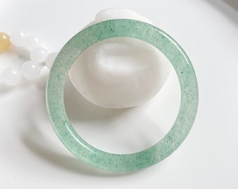 May include: A light green jade bangle bracelet with a smooth, polished finish.