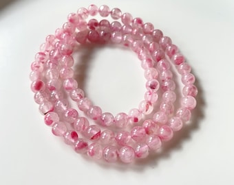 May include: A pink and white crystal bracelet with small round beads. The bracelet is made of natural stones and has a delicate, feminine look.
