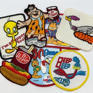 May include: A collection of embroidered patches featuring cartoon characters and logos. Included are patches of Tweety Bird, Fred Flintstone, Garfield, and the Road Runner. Other patches feature Dr. Pepper soda and a bowling theme.
