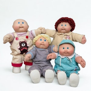 May include: Four Cabbage Patch Kids dolls are displayed. One doll wears overalls with a bear patch, another has curly red hair and a tan outfit, a third doll has blonde hair and a gray outfit, and the last doll wears a blue outfit and a matching hat.