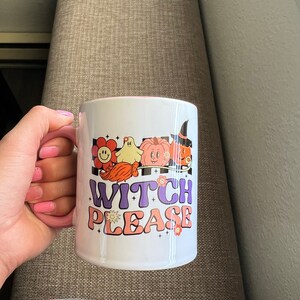 Puede incluir: Taza de cer&aacute;mica blanca con interior y asa rosas, con un dise&ntilde;o retro con las palabras "Witch Please" y gr&aacute;ficos tem&aacute;ticos de Halloween. El dise&ntilde;o incluye una flor sonriente, un fantasma, una calabaza y una bruja.