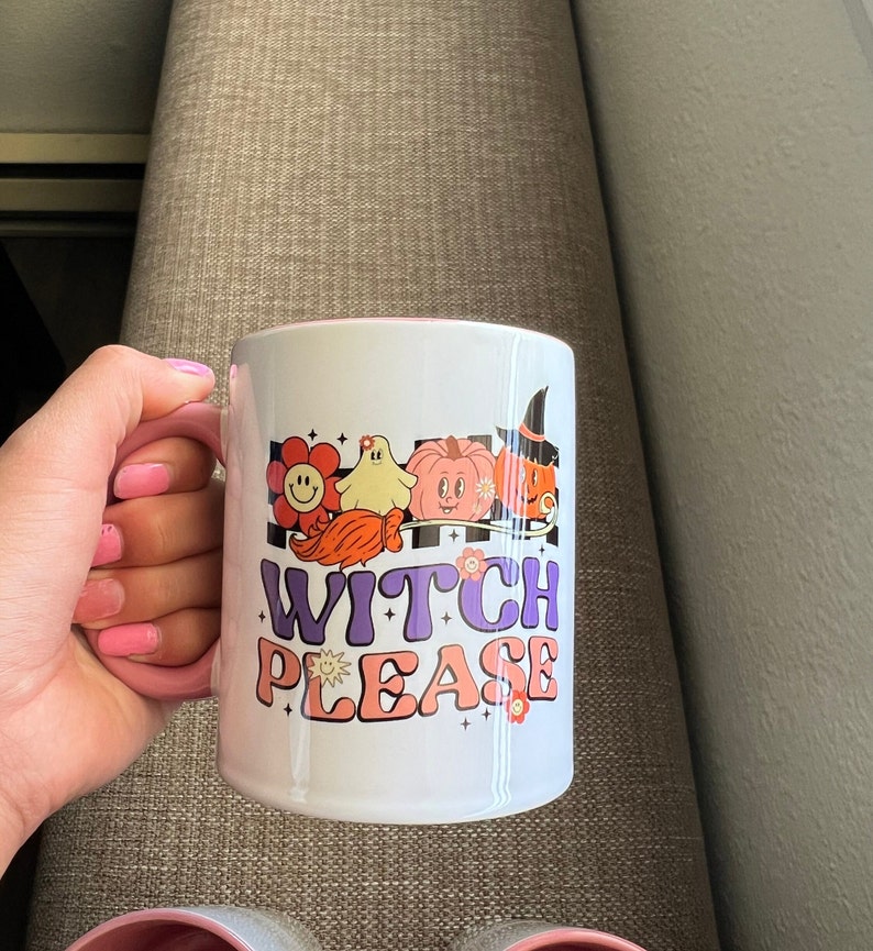Puede incluir: Taza de cer&aacute;mica blanca con interior y asa rosas, con un dise&ntilde;o retro con las palabras "Witch Please" y gr&aacute;ficos tem&aacute;ticos de Halloween. El dise&ntilde;o incluye una flor sonriente, un fantasma, una calabaza y una bruja.