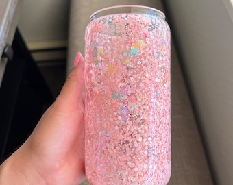 May include: A pink glitter tumbler with a clear lid. The tumbler is filled with pink glitter and iridescent sequins.