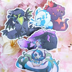 May include: A selection of dragon stickers in various colours. The stickers depict different dragon designs in shades of purple, blue, green, and orange. The dragons have unique features and expressions, set against a backdrop of pink flowers.