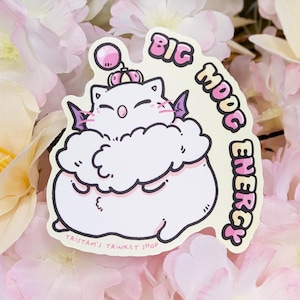 May include: A die-cut sticker featuring a cartoon Moogle character with the text "BIG MOOG ENERGY." The Moogle is white with pink accents and small purple wings. The sticker is surrounded by pink and white flowers.