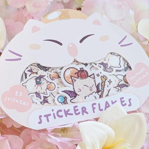 Könnte beinhalten: Eine weiße, katzenförmige Stickerpackung mit 23 Aufklebern, die verschiedene Cartoon-Charaktere zeigen. Auf der Vorderseite steht "STICKER FLAMES". Die Aufkleber sind von rosa und gelben Blumen umgeben.