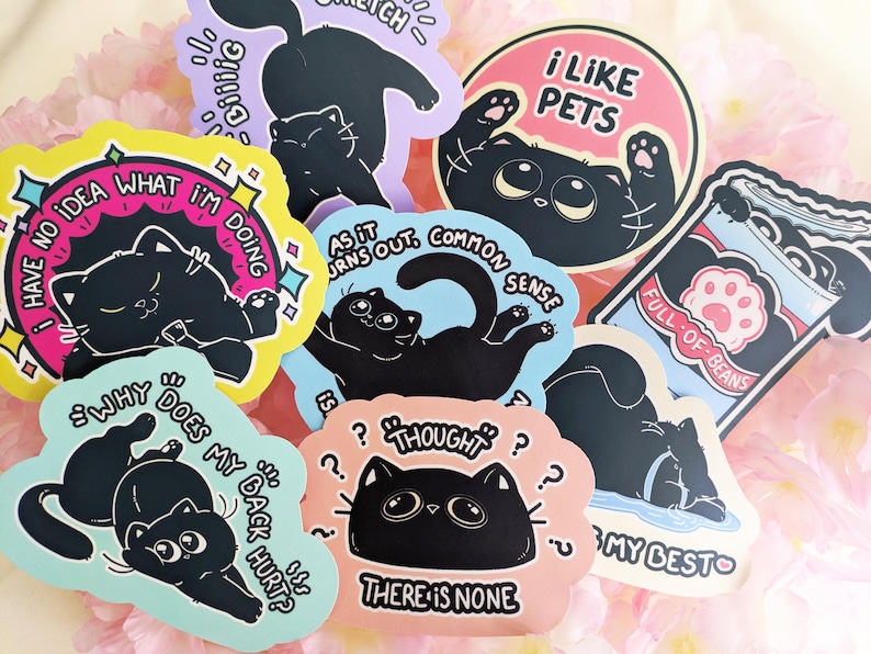 May include: A selection of cat-themed stickers in various colours, each featuring a black cat and humorous text. The stickers include phrases such as "I like pets", "Why does my back hurt?" and "Full of beans".