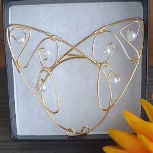 May include: Gold wire cat ears with white pearl beads, displayed in a black box with a yellow flower.