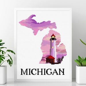 Puede incluir: Un patrón de punto de cruz del estado de Michigan con un faro en el centro. El estado está delineado en rosa y morado, y el faro es blanco con un techo rojo. La palabra "MICHIGAN" está escrita debajo del estado.