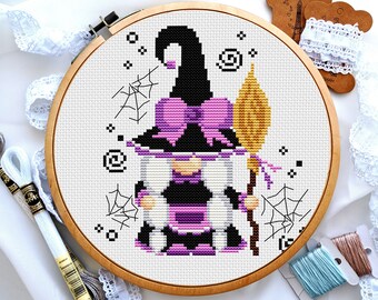 Può includere: Schema di punto croce di un gnomo strega viola e nero con una scopa e ragnatele. Lo gnomo indossa un cappello viola con un fiocco e un vestito viola.