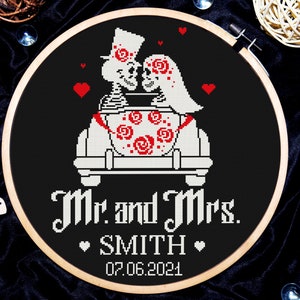 May include: A black and white cross-stitch embroidery design of a skeleton couple in a car with the text "Mr. and Mrs. SMITH 07.06.2021".
