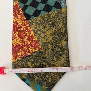 May include: A patchwork tie with various patterns and colors. The tie features sections of black and teal checkerboard, floral designs, and stripes. The tie is approximately 5 inches long.