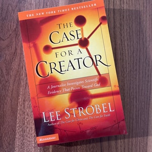 May include: The Case for a Creator book cover with a red, orange, and yellow color scheme. The title is "The Case for a Creator" with the subtitle "A Journalist Investigates Scientific Evidence That Points Toward God". The author is Lee Strobel. The book cover features a stylized chemical structure.