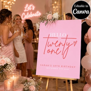 May include: A pink rectangular birthday sign on a gold easel featuring the text "HELLO twenty one" in red script, "SARAH'S 30TH BIRTHDAY" and "SEPTEMBER 6TH 2024" in white, topped with a floral arrangement of pink and white roses and baby's breath.