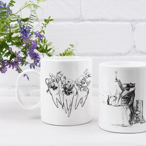 Op de afbeelding: Twee witte keramische mokken met zwart-wit illustraties. De ene mok heeft een groep cartoon tanden met gezichten en armen, terwijl de andere mok een cartoon dier in een pak laat zien dat een glas wijn vasthoudt.