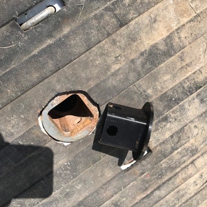 May include: A close-up of a black metal hitch receiver and a hole in a truck bed. The hitch receiver is designed to connect to a trailer.