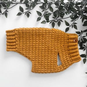 Peut inclure: Un pull en crochet jaune moutarde pour chien avec un trou pour la laisse.