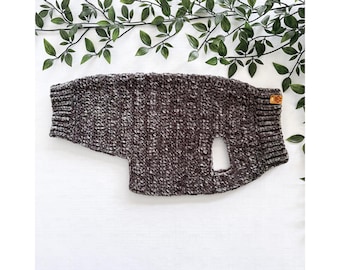 May include: A brown and white knitted dog sweater with a hole for the leash.