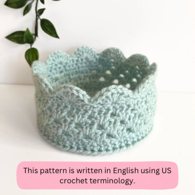 May include: A light blue crocheted crown with a scalloped edge. This pattern is written in English using US crochet terminology.