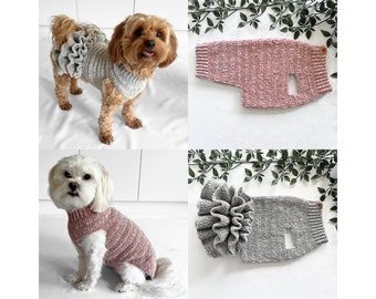 May include: Two knitted dog sweaters with a large flower detail. One sweater is gray and the other is pink.