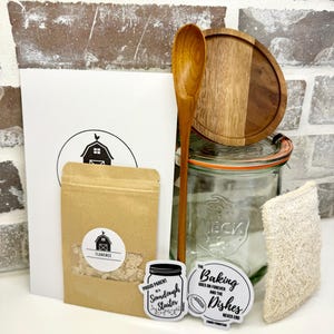 Puede incluir: Un kit de masa madre con un frasco de vidrio, una cuchara de madera, una bolsa de papel marr&oacute;n con masa madre, una tapa de madera, una esponja de luffa natural y dos pegatinas que dicen "Orgulloso padre de una masa madre" y "La reposter&iacute;a contin&uacute;a para siempre y los platos nunca terminan".