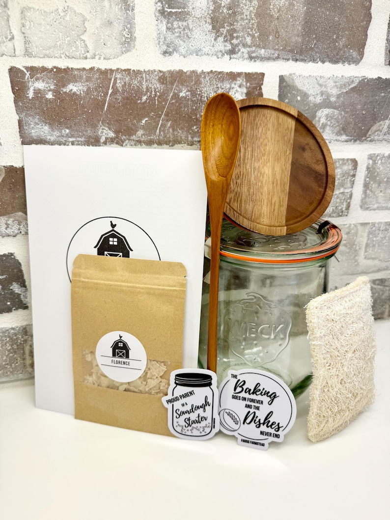 Puede incluir: Un kit de masa madre con un frasco de vidrio, una cuchara de madera, una bolsa de papel marr&oacute;n con masa madre, una tapa de madera, una esponja de luffa natural y dos pegatinas que dicen "Orgulloso padre de una masa madre" y "La reposter&iacute;a contin&uacute;a para siempre y los platos nunca terminan".