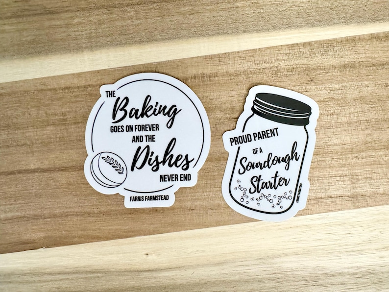 Puede incluir: Dos pegatinas blancas con texto negro y gr&aacute;ficos. La primera pegatina dice "The Baking Goes On Forever And The Dishes Never End" con un peque&ntilde;o gr&aacute;fico de una hogaza de pan. La segunda pegatina dice "Proud Parent Of A Sourdough Starter" con un gr&aacute;fico de un frasco con burbujas.
