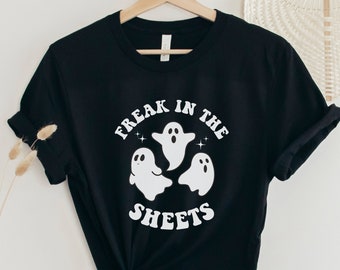 以下が含まれることがあります： 白い幽霊3匹と「Freak in the Sheets」という文字が書かれた黒いTシャツ。