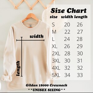 May include: A size chart for a Gildan 18000 Crewneck sweatshirt, showing the width and length measurements in inches for sizes S through 5XL. The chart is printed on a beige sweatshirt.