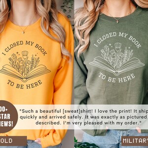 K&ouml;nnte beinhalten: Zwei Sweatshirts mit einem Buch- und Blumendesign. Der Text auf den Sweatshirts lautet "Ich habe mein Buch geschlossen, um hier zu sein". Ein Sweatshirt ist goldfarben und das andere ist milit&auml;rgr&uuml;n.
