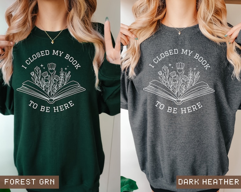 K&ouml;nnte beinhalten: Ein gr&uuml;nes und ein dunkel-heather-graues Sweatshirt mit einem wei&szlig;en Grafikdesign eines offenen Buches, aus dem Blumen wachsen. Der Text auf dem Sweatshirt lautet "Ich habe mein Buch geschlossen, um hier zu sein".