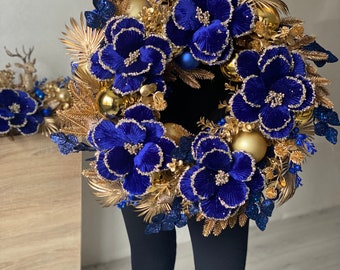 Luxury wreath on the front door with pine cones, blue berries and golden branches, elegant wreath.